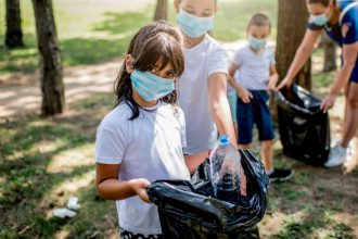 niños y niñas de la escuela recogiendo la basura juntos mientras limpian el parque público